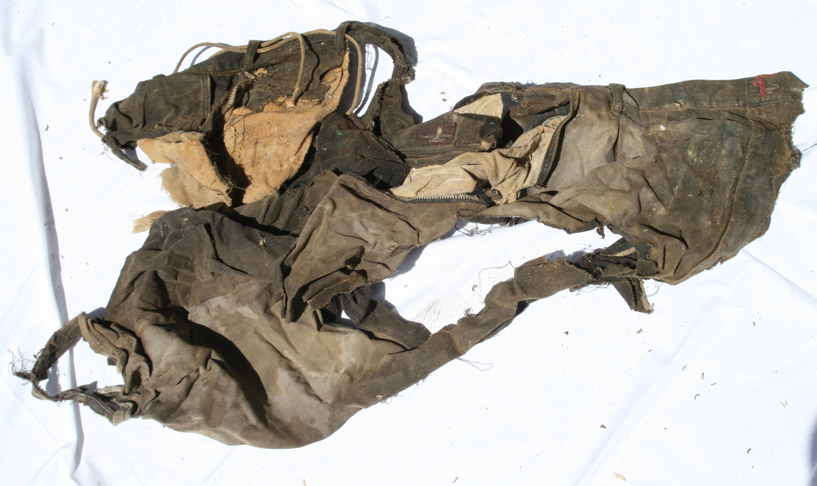 NamUs UP10065 — tattered denim pants, with rope belt and red-thread repair at fly